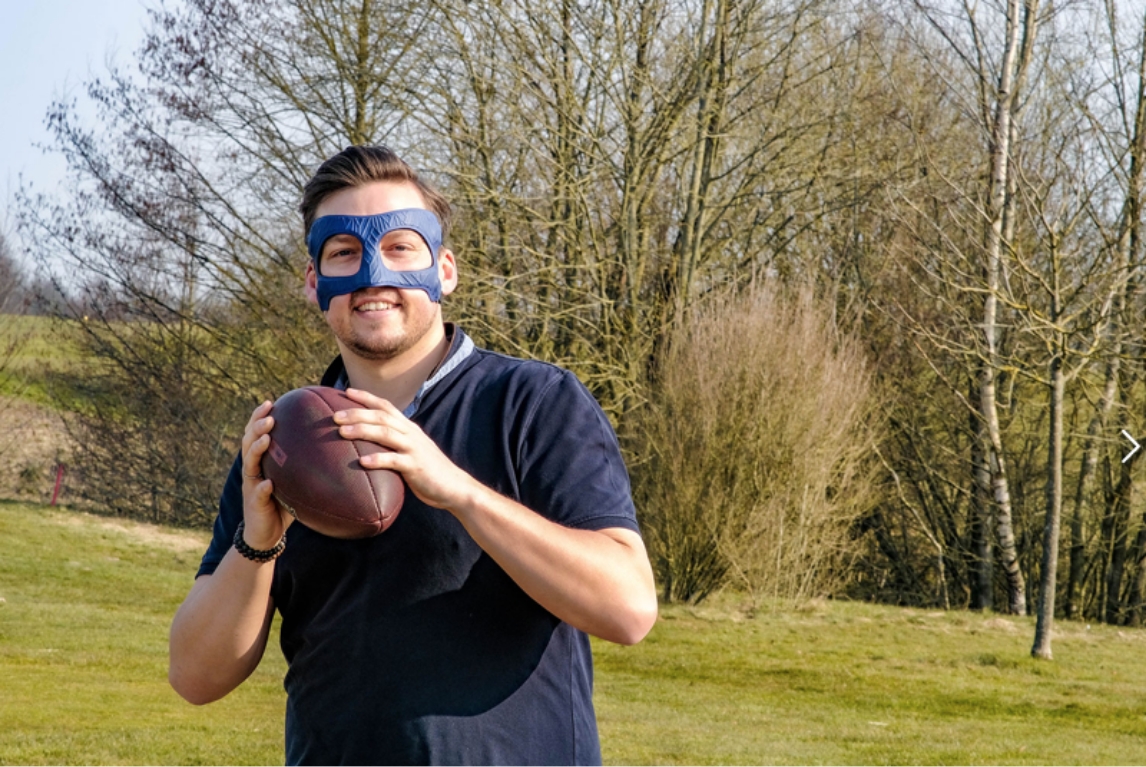 Mann trägt Kopforthese und wirft einen Football