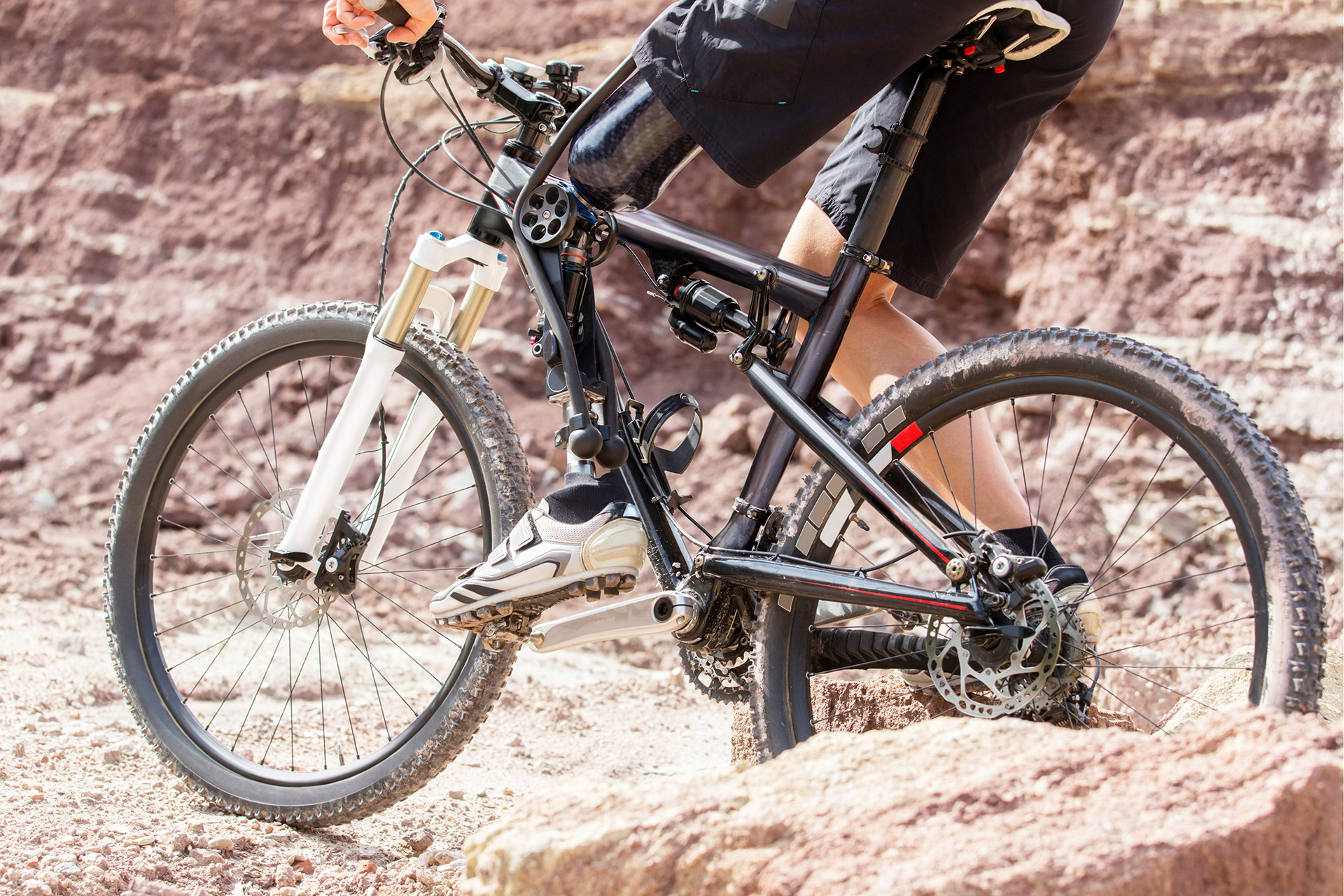 Person mit Oberschenkelorthese fährt Mountainbike in den Bergen